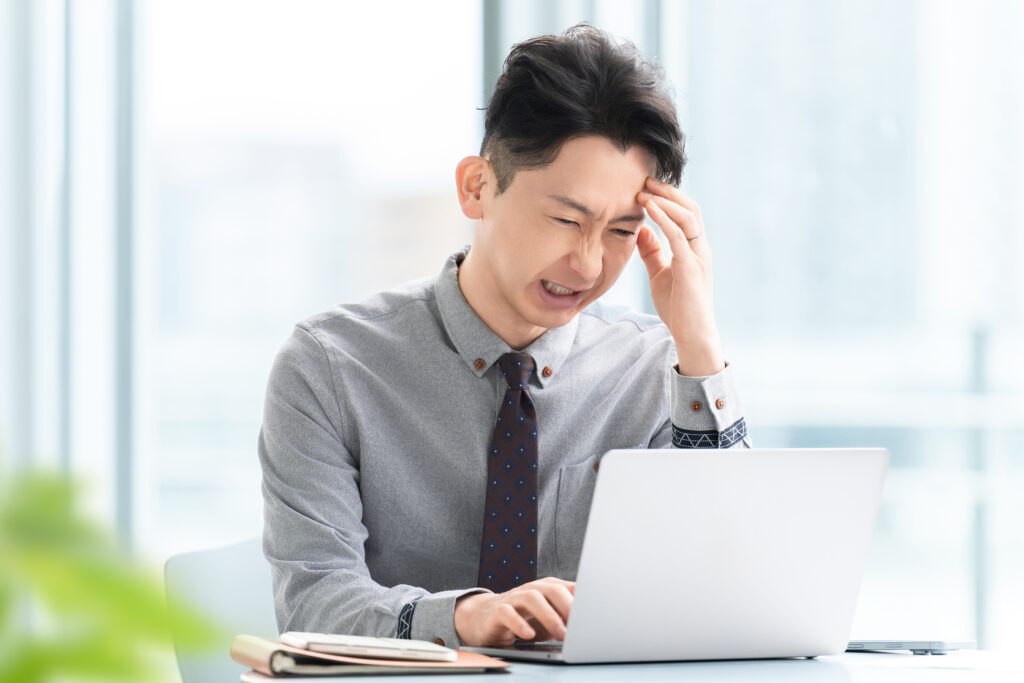 パソコンを使いながら悩む男性