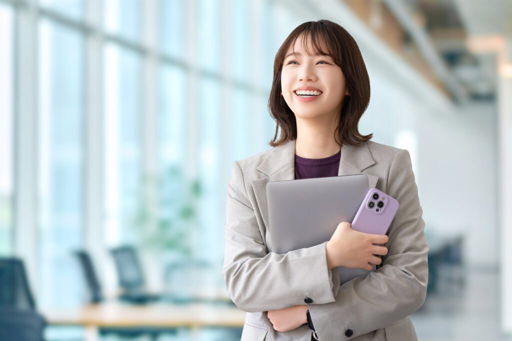 パソコンとスマホを持つ笑顔の女性