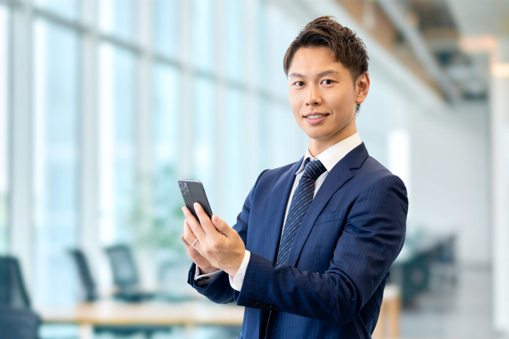 スマホを持つ笑顔の男性ビジネスマン