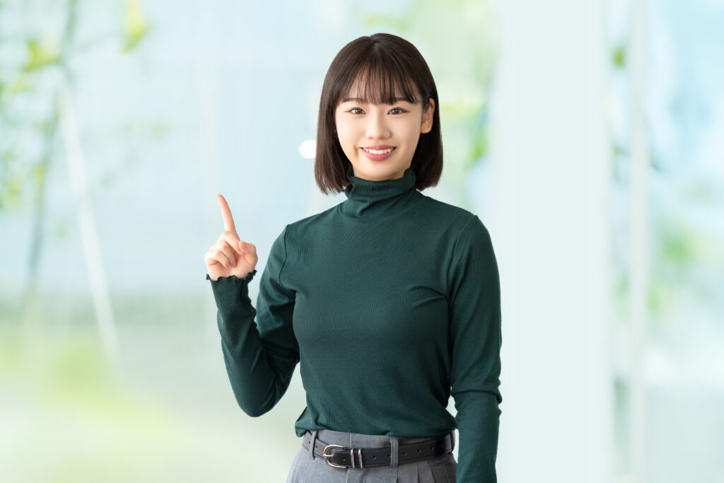 人差し指を立てて案内する笑顔の女性