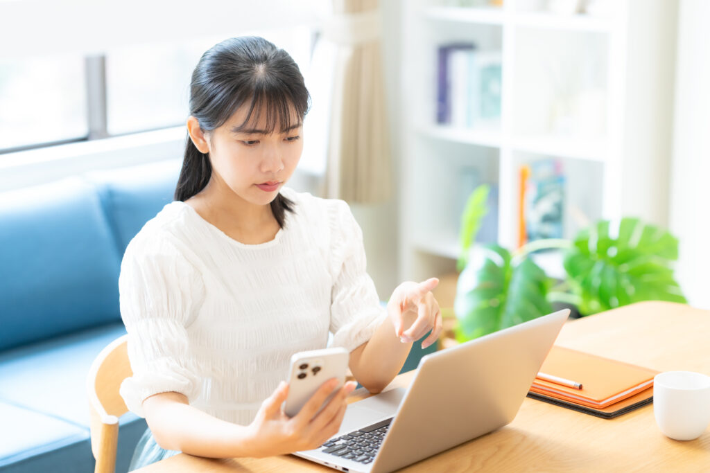 リビングでパソコンを見る大学生の女性