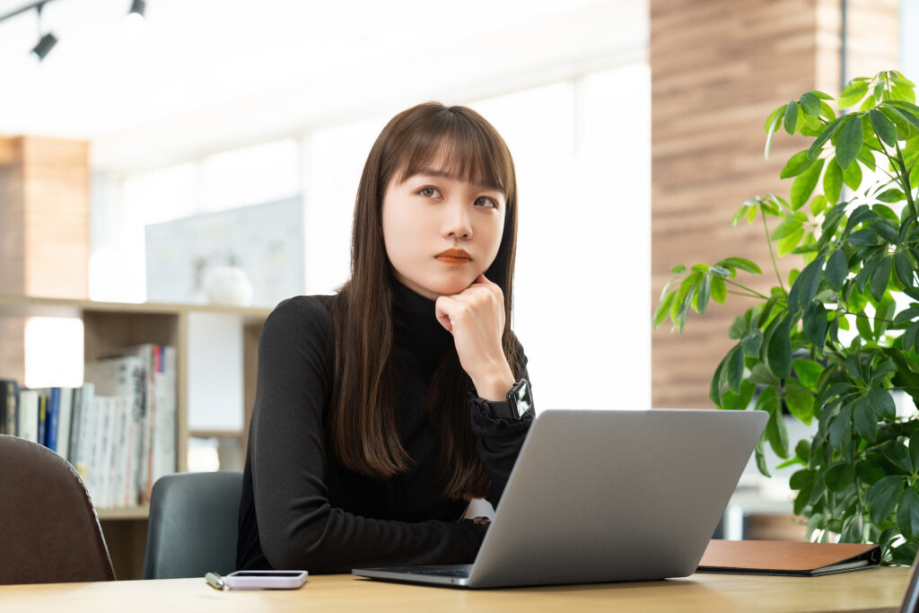 パソコンを使いながら考える女性