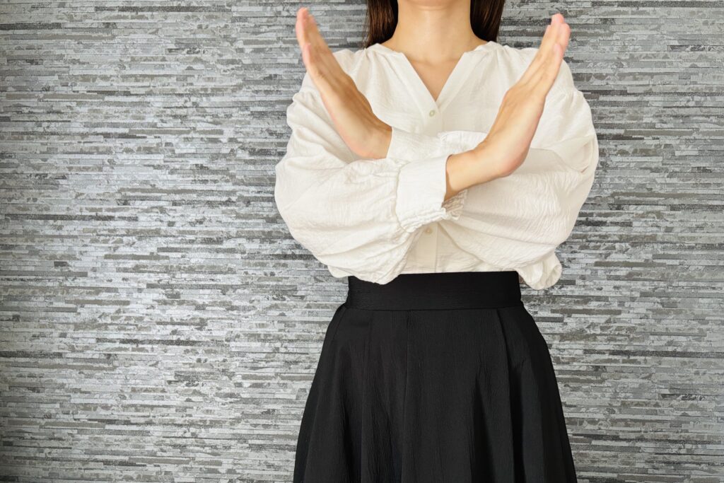 手でバツマークをする女性