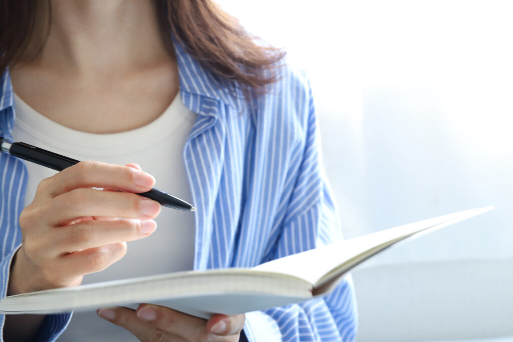 手帳とぺんを持った女性