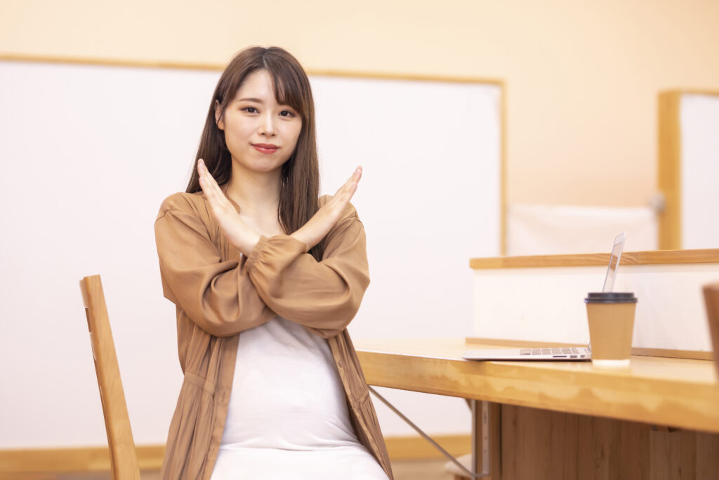 女性が手でバツじるしする