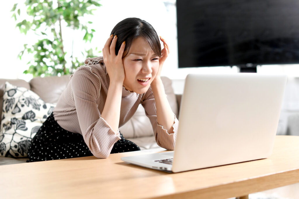 ノートパソコンの前でトラブル(ストレス)を抱える若い女性