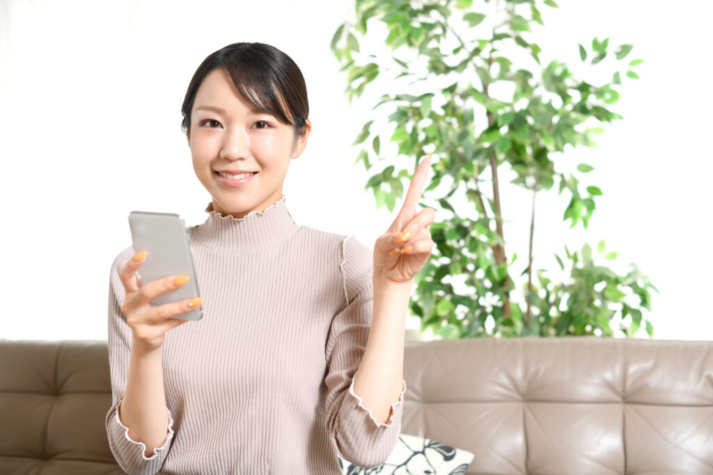 ノートパソコンと人差し指を立てる笑顔の若い女性