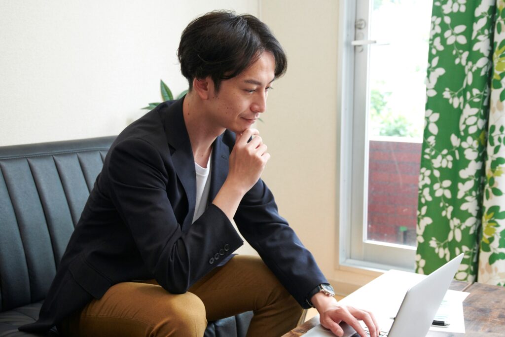 ソファーでノートパソコンを使う男性