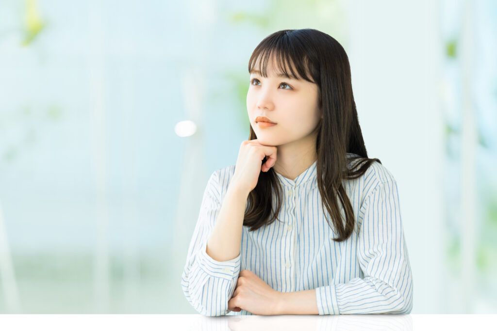 肘をついて考えごとをする女性
