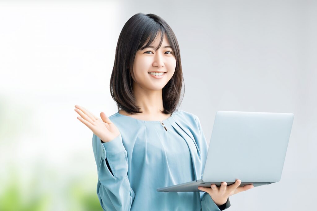 パソコンを持って案内をする笑顔の女性