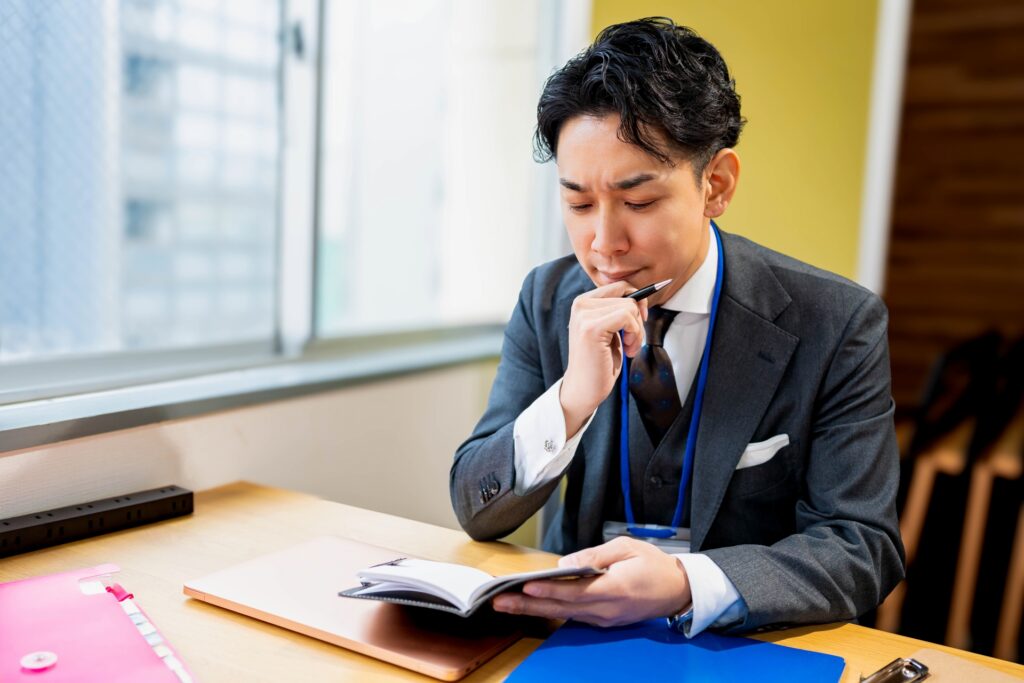 手帳を見て悩むビジネスマン