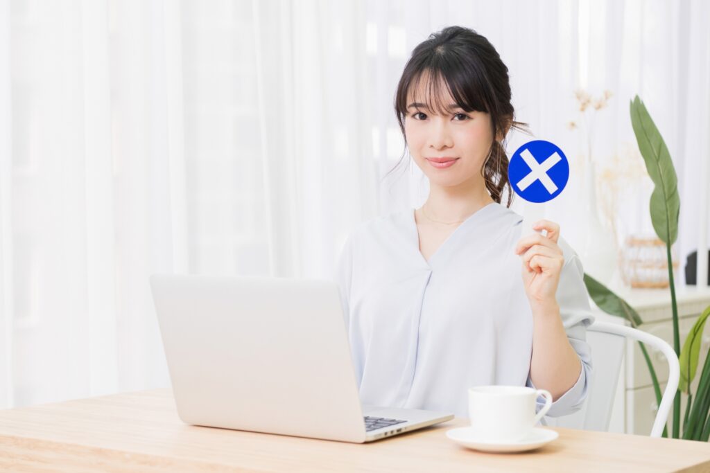 部屋でノートパソコンを使いながらNGのプラカードを持つ若い女性