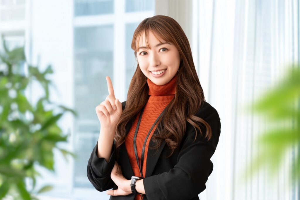 人差し指を立てて案内する笑顔の女性