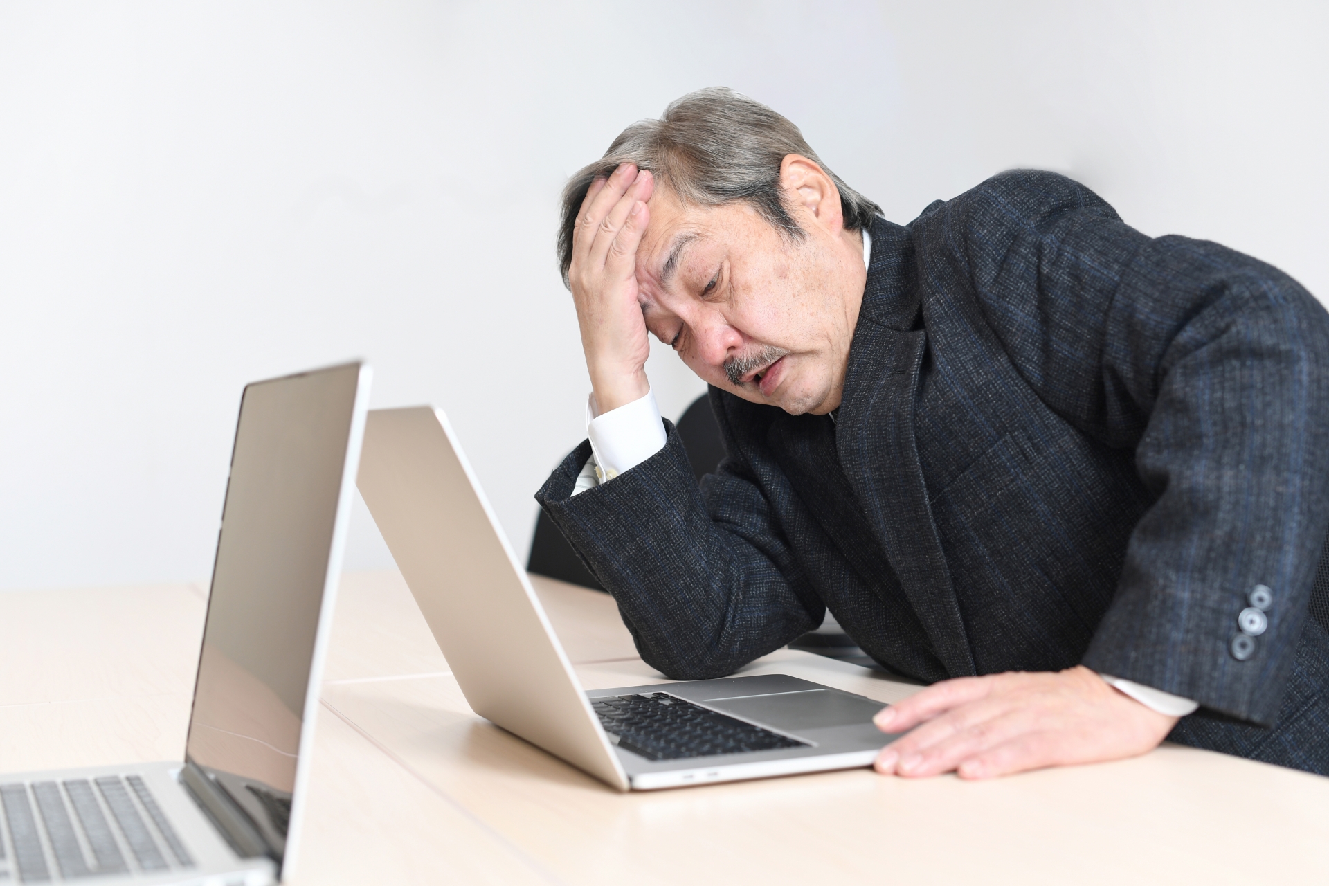 パソコンの前で頭を抱える中高年の会社員