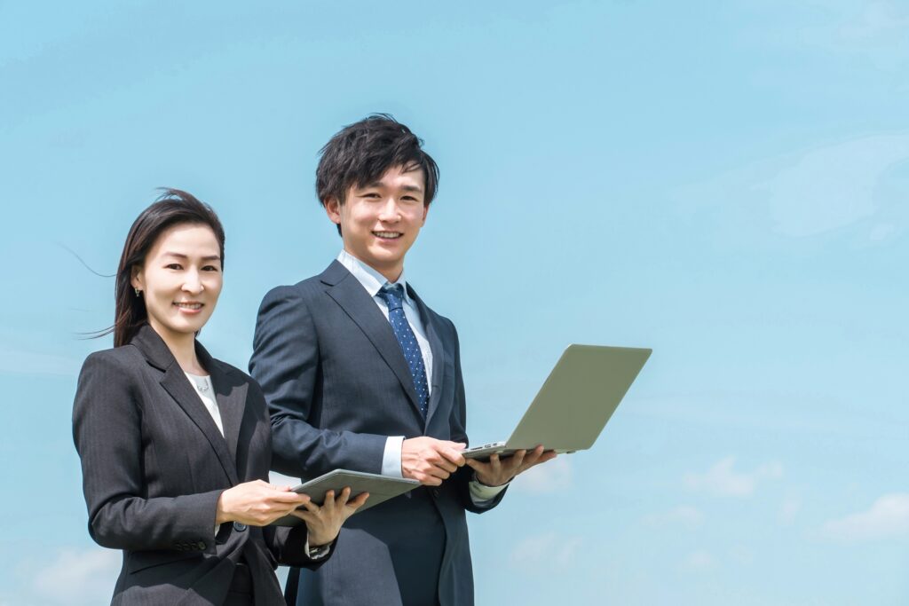 就職・転職・青空の中に立つスーツ姿の男女