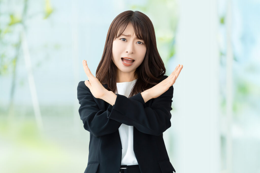 手でバツのポーズをして怒る女性