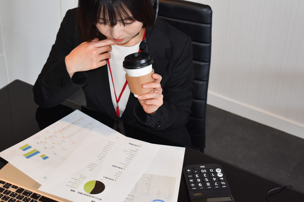 コーヒーを持って資料を確認する女性社員