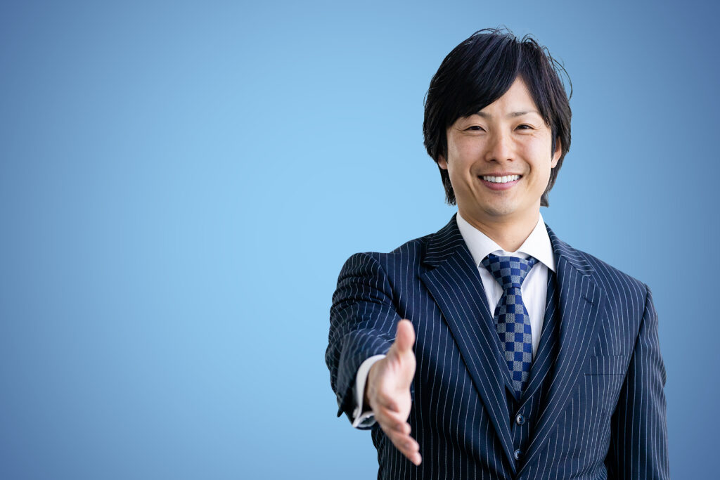 笑顔で握手を求めるビジネススーツの男性
