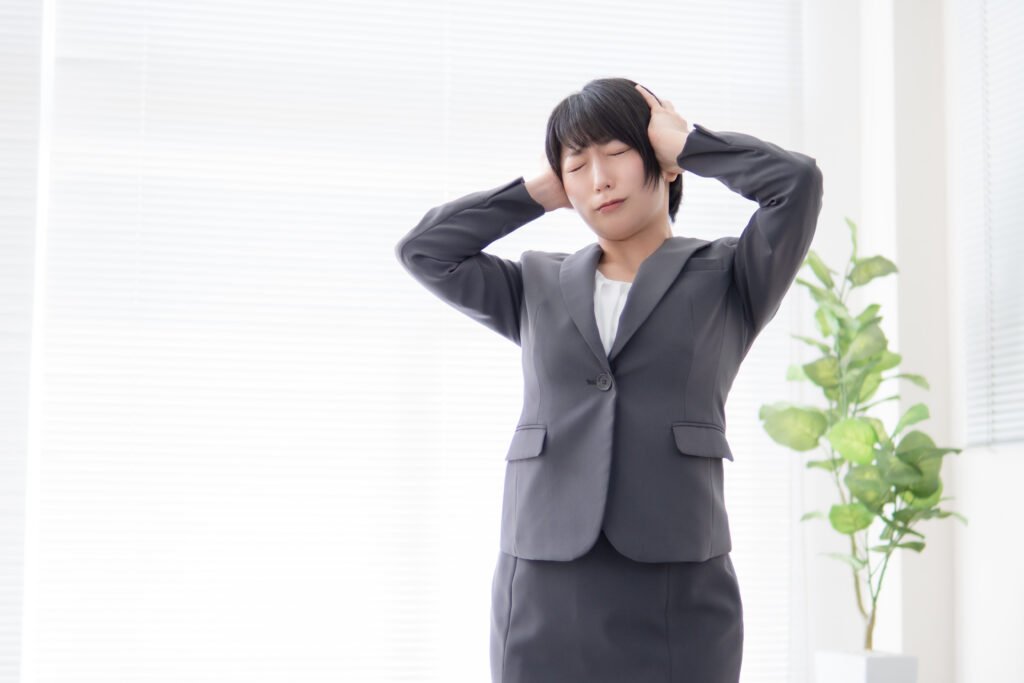 頭を抱えて悩むスーツ姿の女性