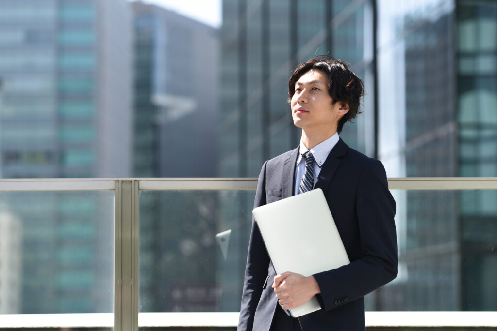  屋外でPCを持つスーツ姿のビジネスマン