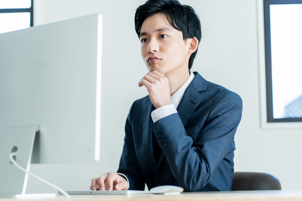 パソコン作業をする悩む若い男性