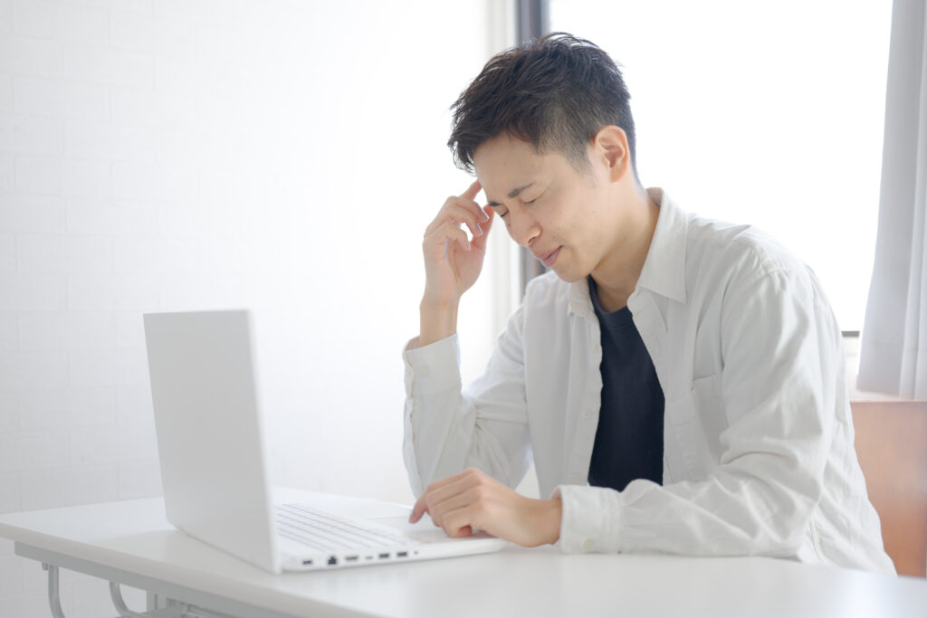 頭に手を当て顔を歪める男