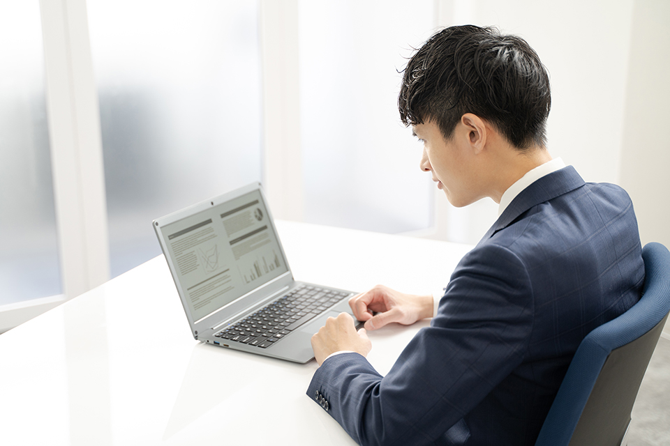 ノートパソコンで資料作成時に悩む男性