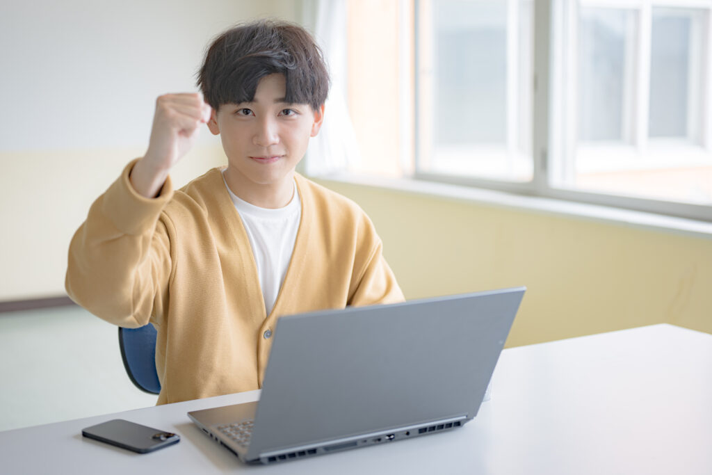 PCとガッツポーズする爽やかな男性