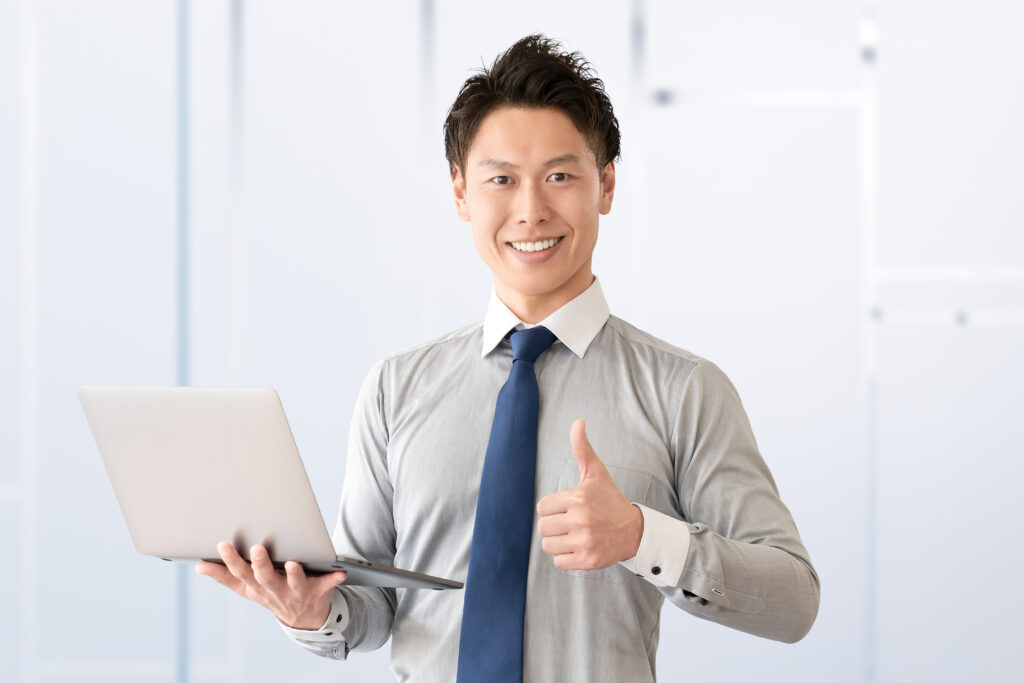 パソコンを持っていいねのポーズをする男性