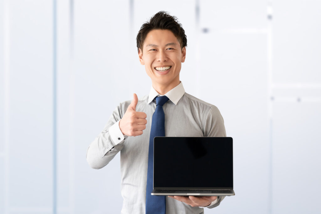 パソコンを持っていいねのポーズをする男性