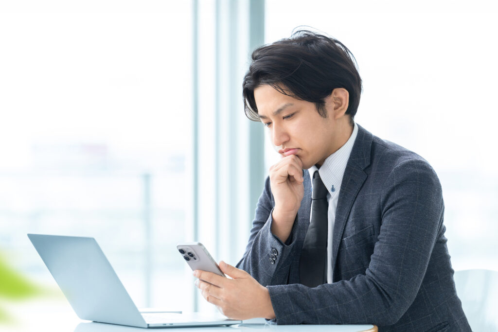 スマホを見て考える男性ビジネスマン