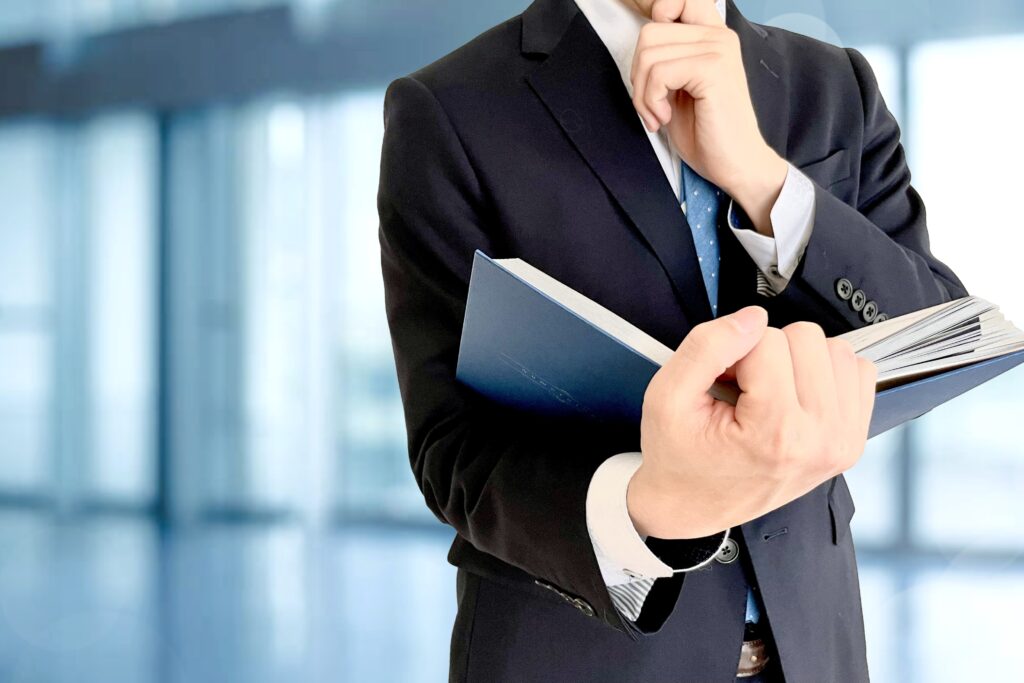 本を開くビジネスマンと会社の背景