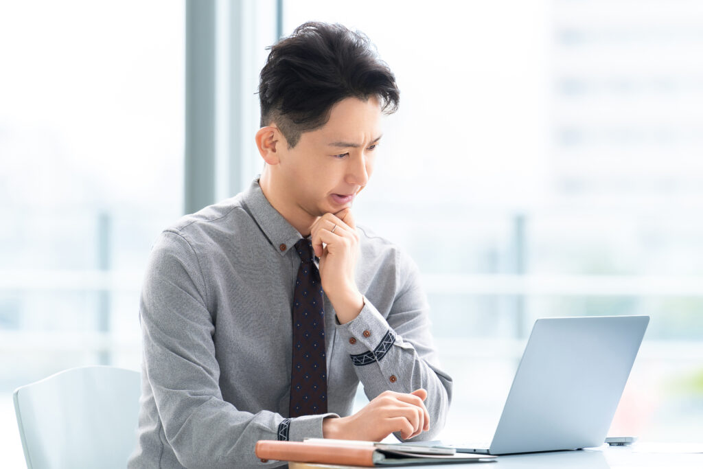 パソコンを使いながら悩む男性ビジネスマン