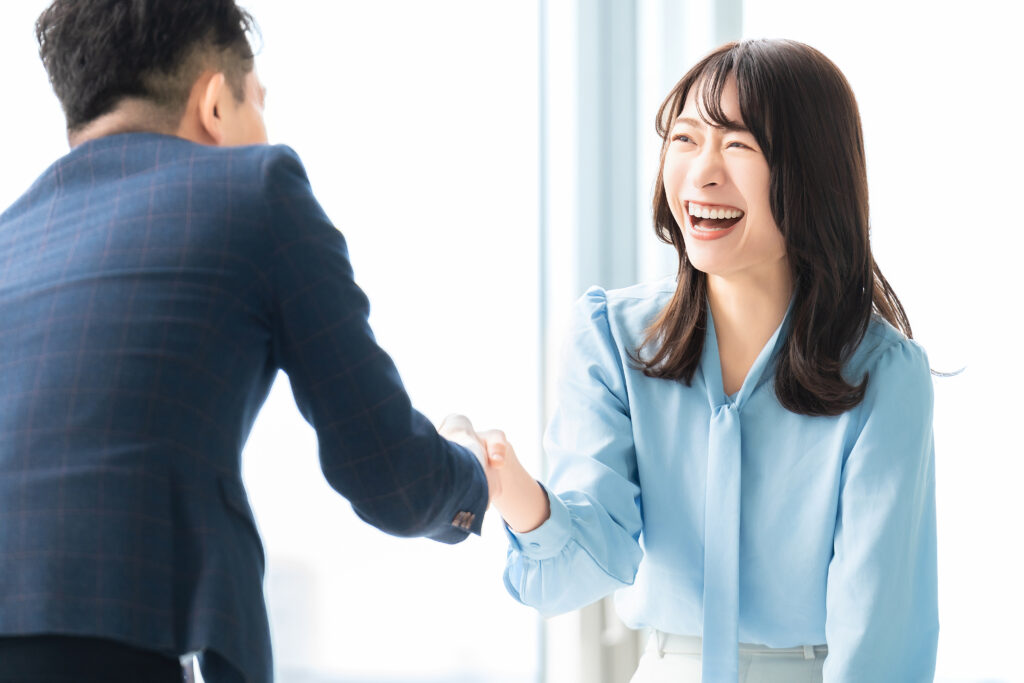 笑顔で握手をする男女2人のビジネスマン