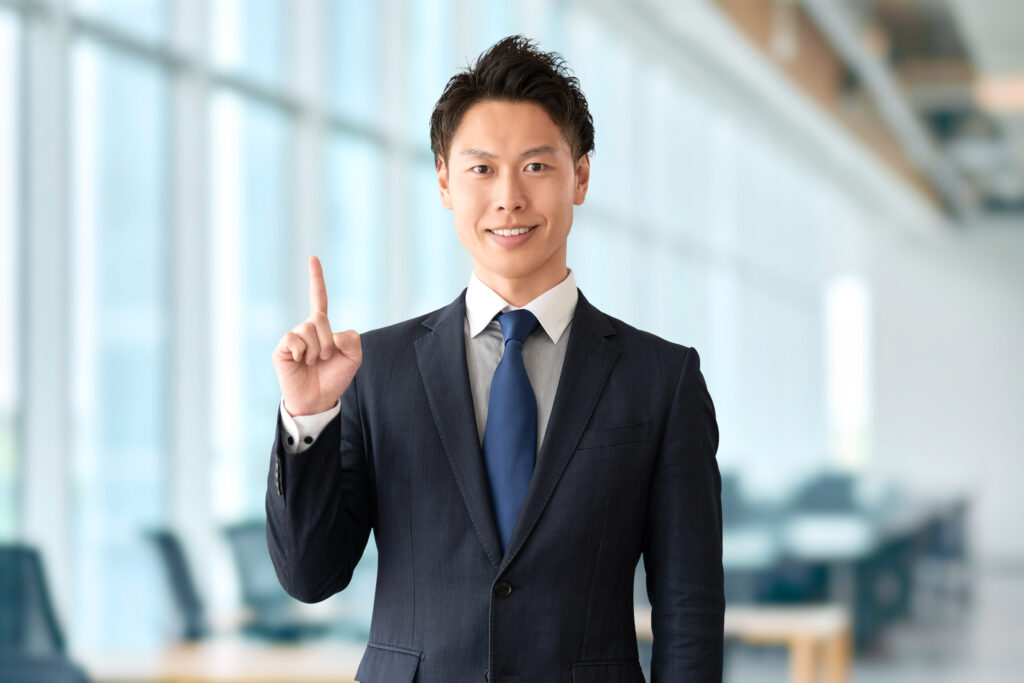 人差し指を立てて案内する男性ビジネスマン