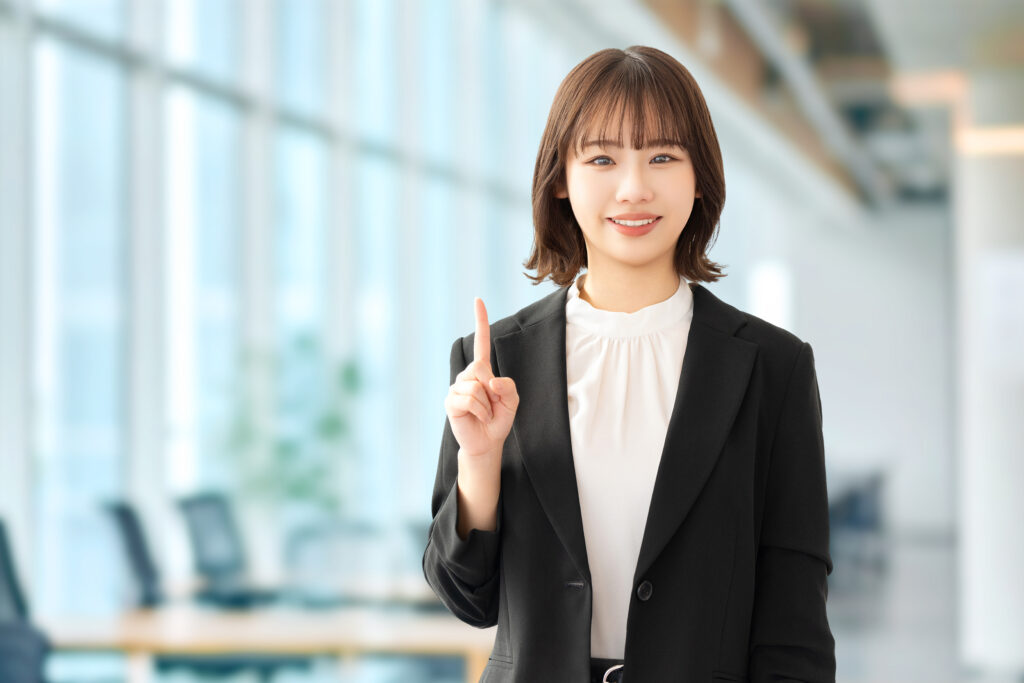 人差し指を立てて案内する笑顔の女性