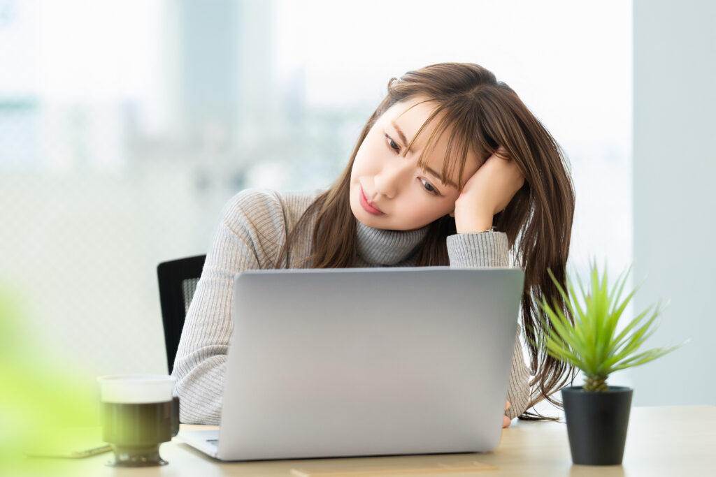 パソコンの画面を見ながら悩む女性