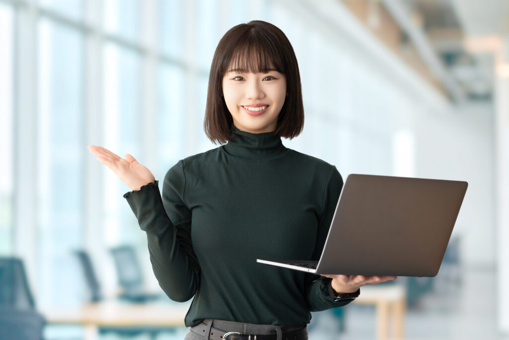パソコンを持って案内をする笑顔の女性