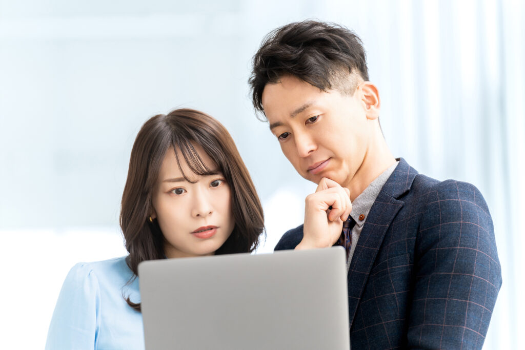 パソコンを見て考える男女のビジネスマン
