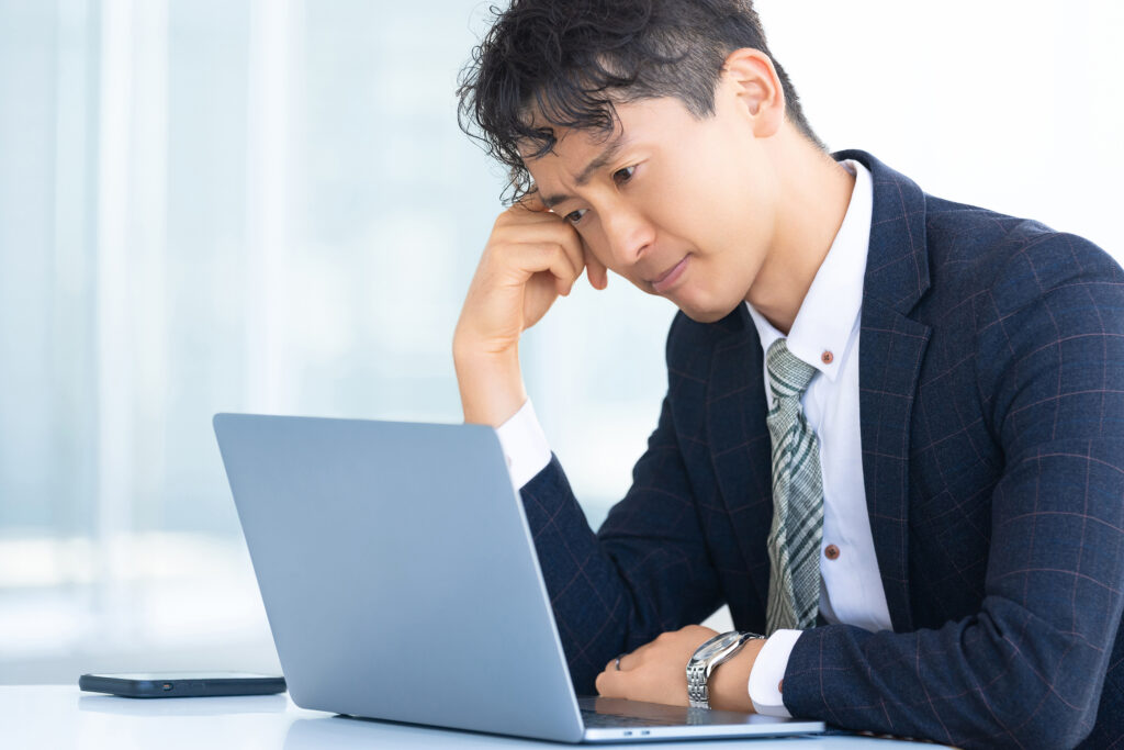 パソコンを使いながら悩む男性ビジネスマン