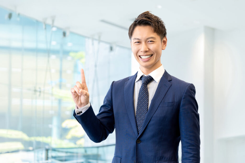 人差し指を立てて案内する男性ビジネスマン