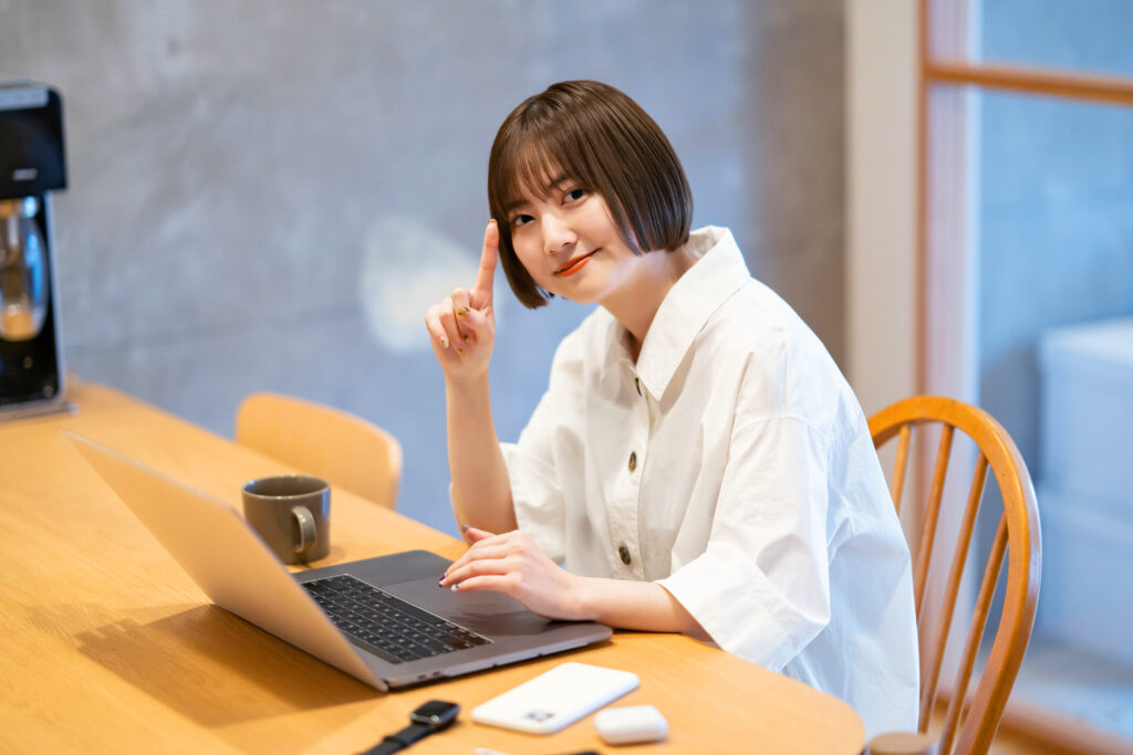 自宅の部屋でノートPCを操作する若い女性