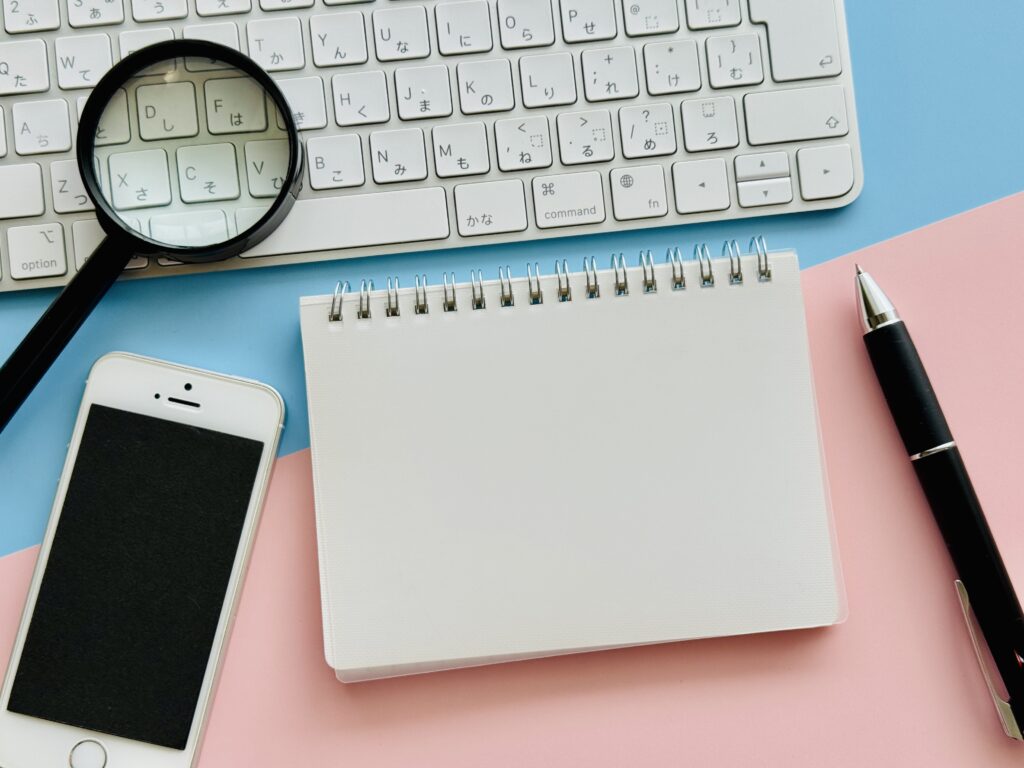 虫眼鏡とPC、スマホ、白紙のノート