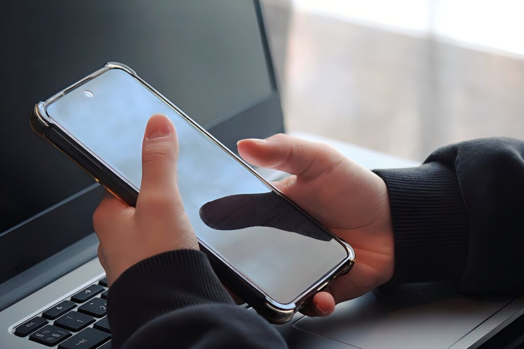 携帯を操作する手元とノートパソコン 1