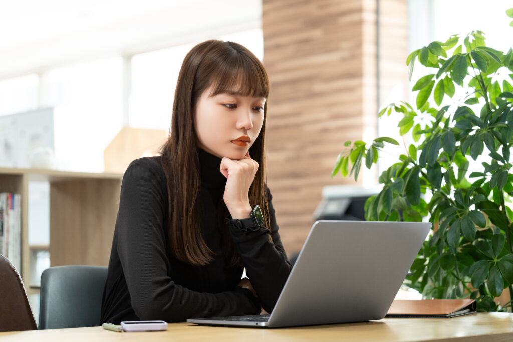 パソコンの画面を見ながら考える女性