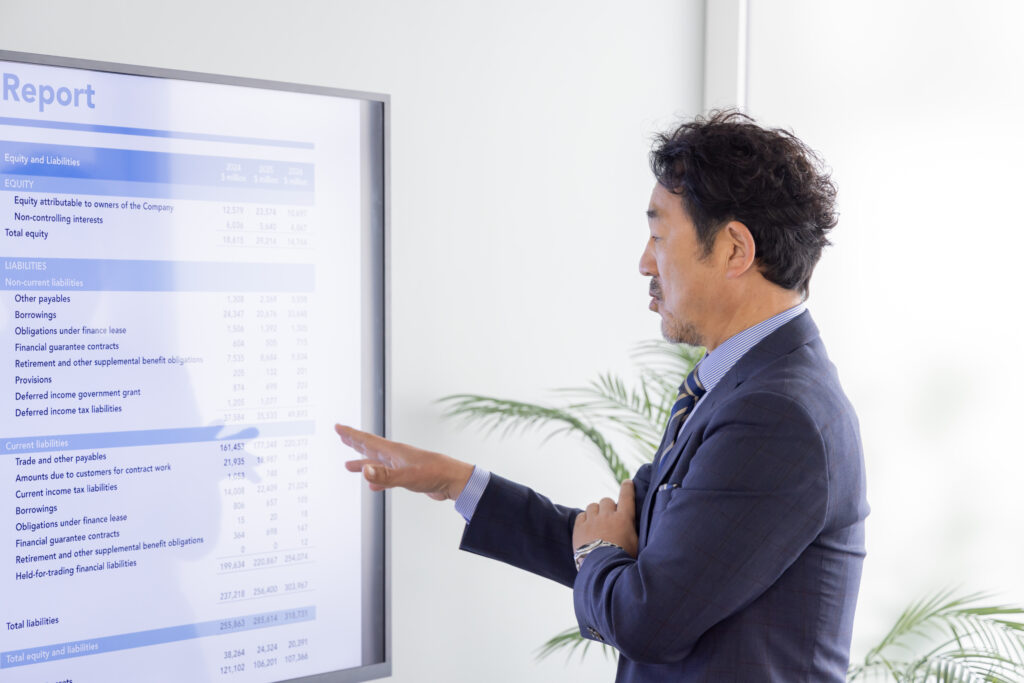 大画面モニターで説明するビジネスパーソン