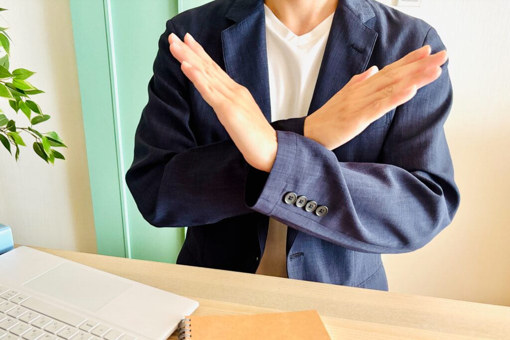 手でバツマークを作る男性