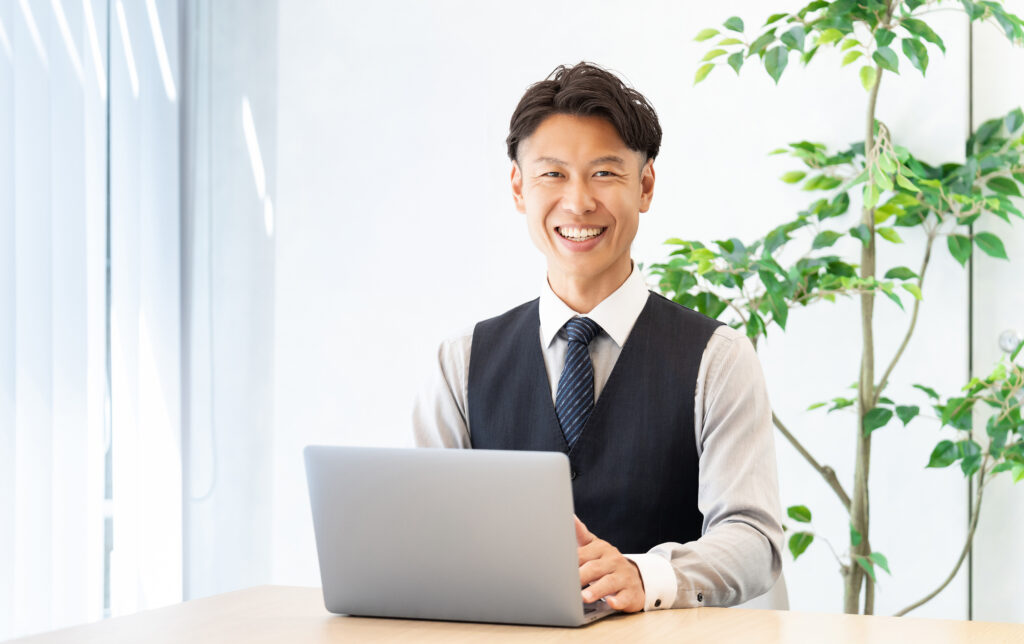 パソコンを使う笑顔の男性ビジネスマン