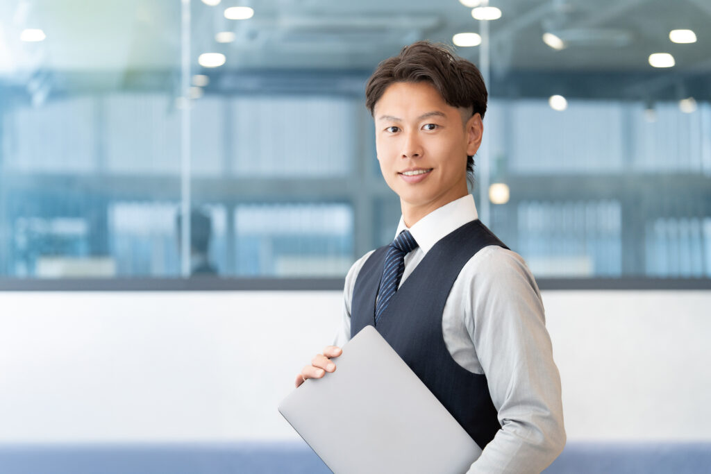 パソコンを持つ笑顔の男性ビジネスマン