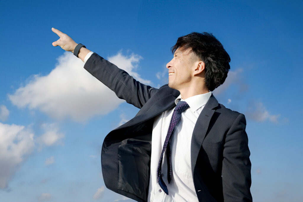 空を指さすビジネスマン